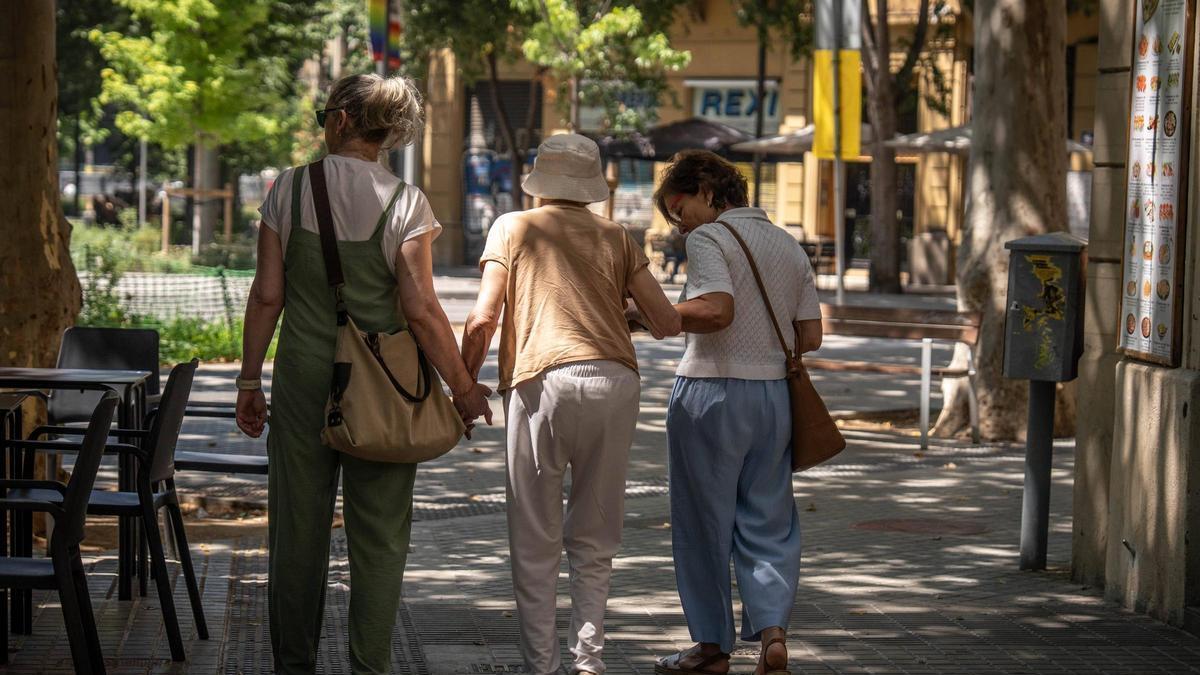 Tres personas pasean por las calles de Barcelona durante la ola de calor.