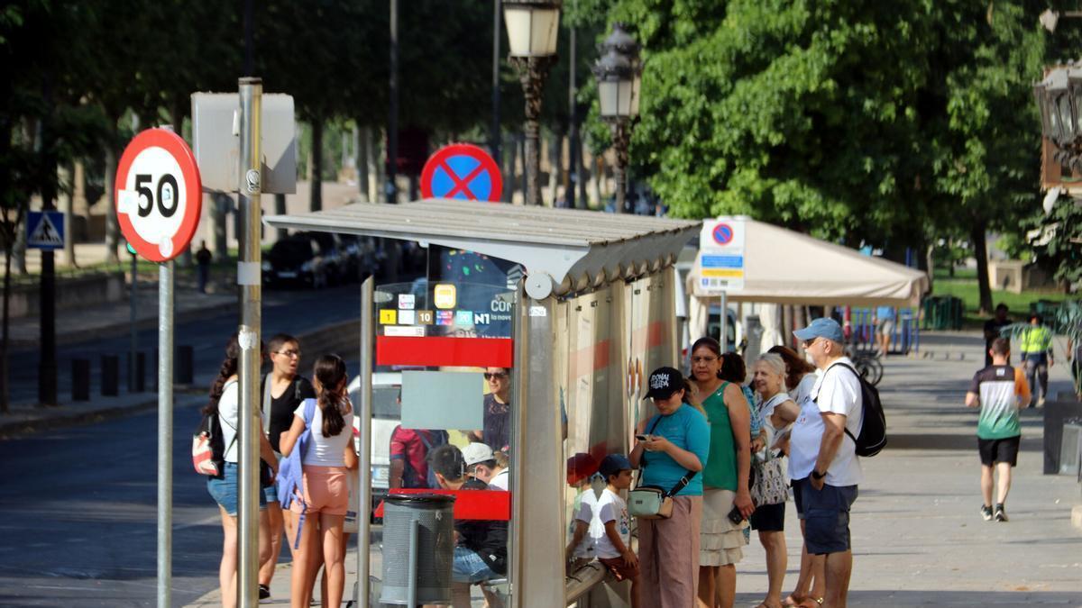Varias personas se refugian a la sombra de una parada de autobús en la avenida Blondel de Lleida durante la ola de calor