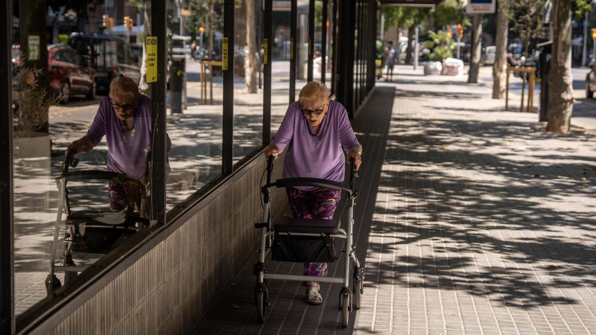 Una mujer camina por una zona de sombra para refugiarse del calor de Barcelona.