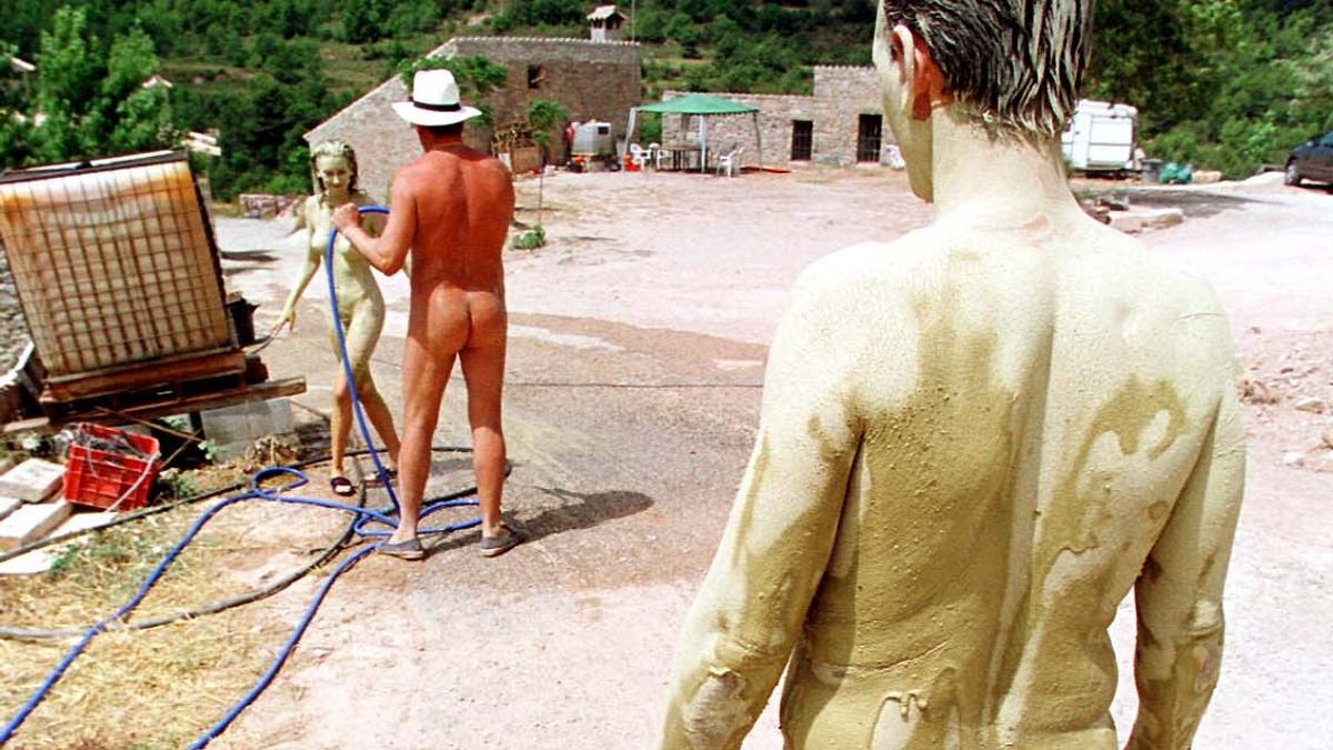 Unos naturistas toman un baño de arcilla and se lo quitan con una manguera in el pueblo naturista de El Fonoll.