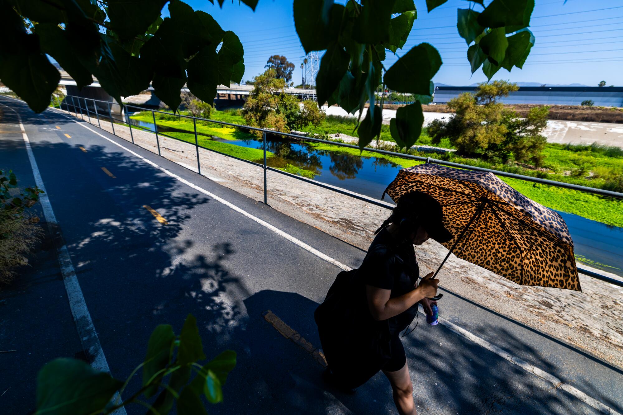 Un piéton marche avec un parapluie sur le chemin de la rivière LA