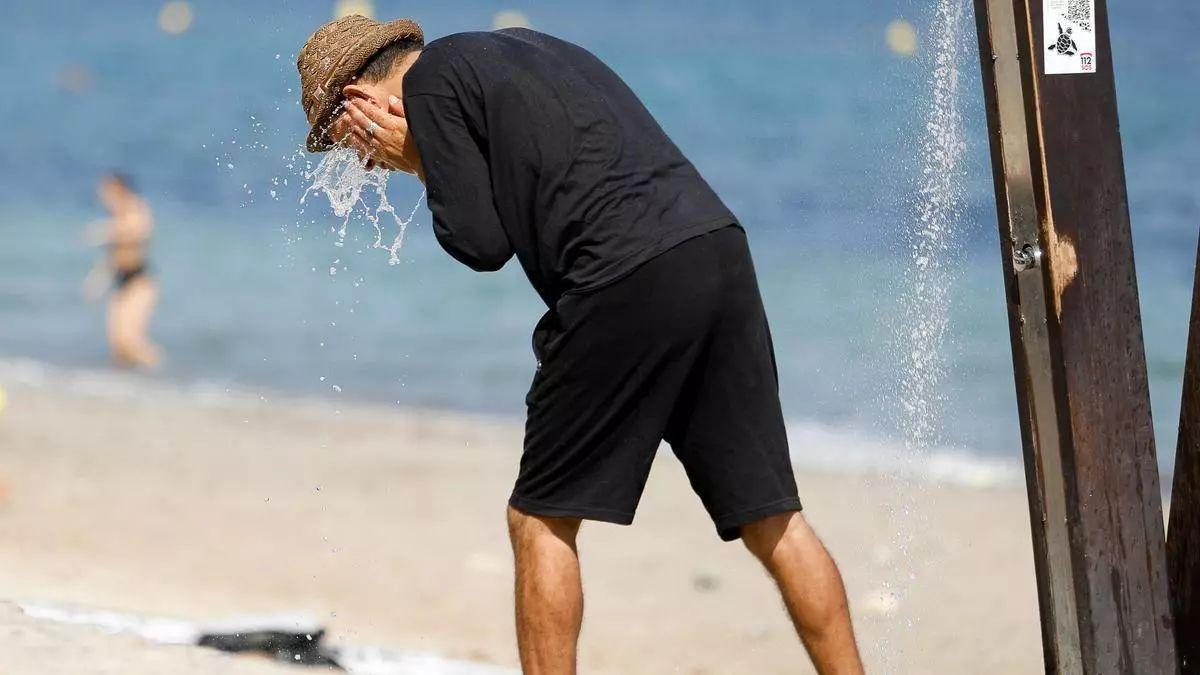 Un homme se rafraîchit sur une plage este verano
