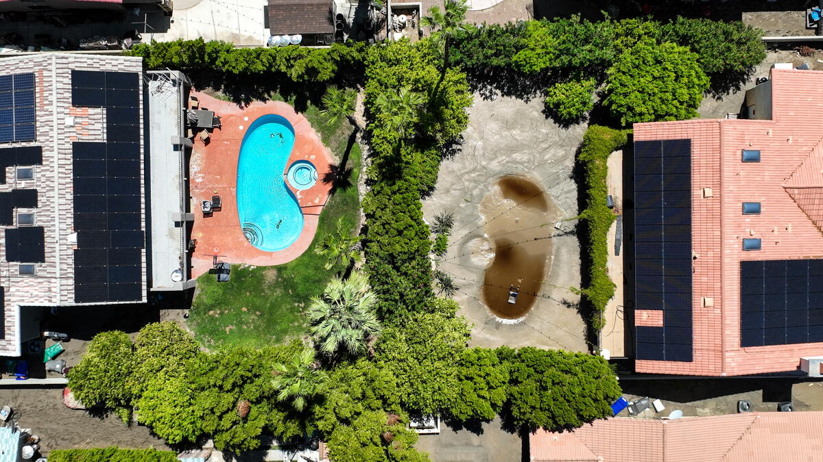 Photo aérienne montrant une piscine de jardin recouverte de boue provenant des eaux de crue.