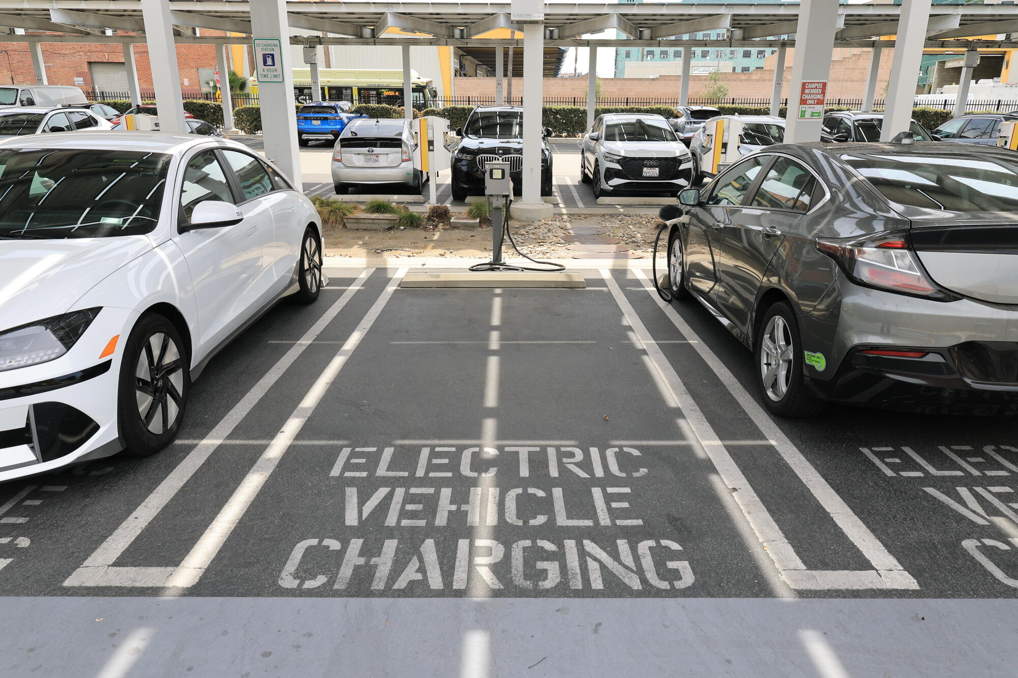 Deux voitures électriques en cours de recharge, flanquant une place de parking vide réservée à la recharge des véhicules électriques