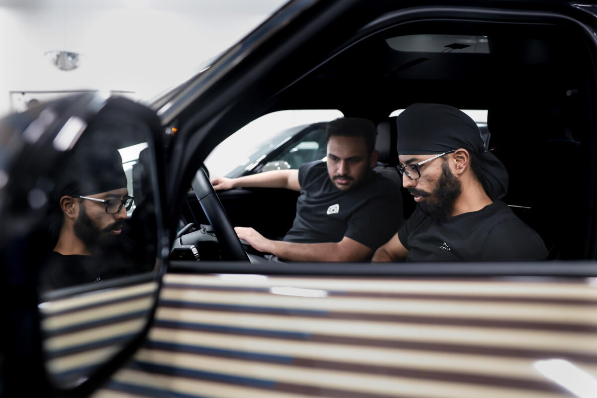 Deux hommes assis à l'avant d'une voiture, regardant les commandes