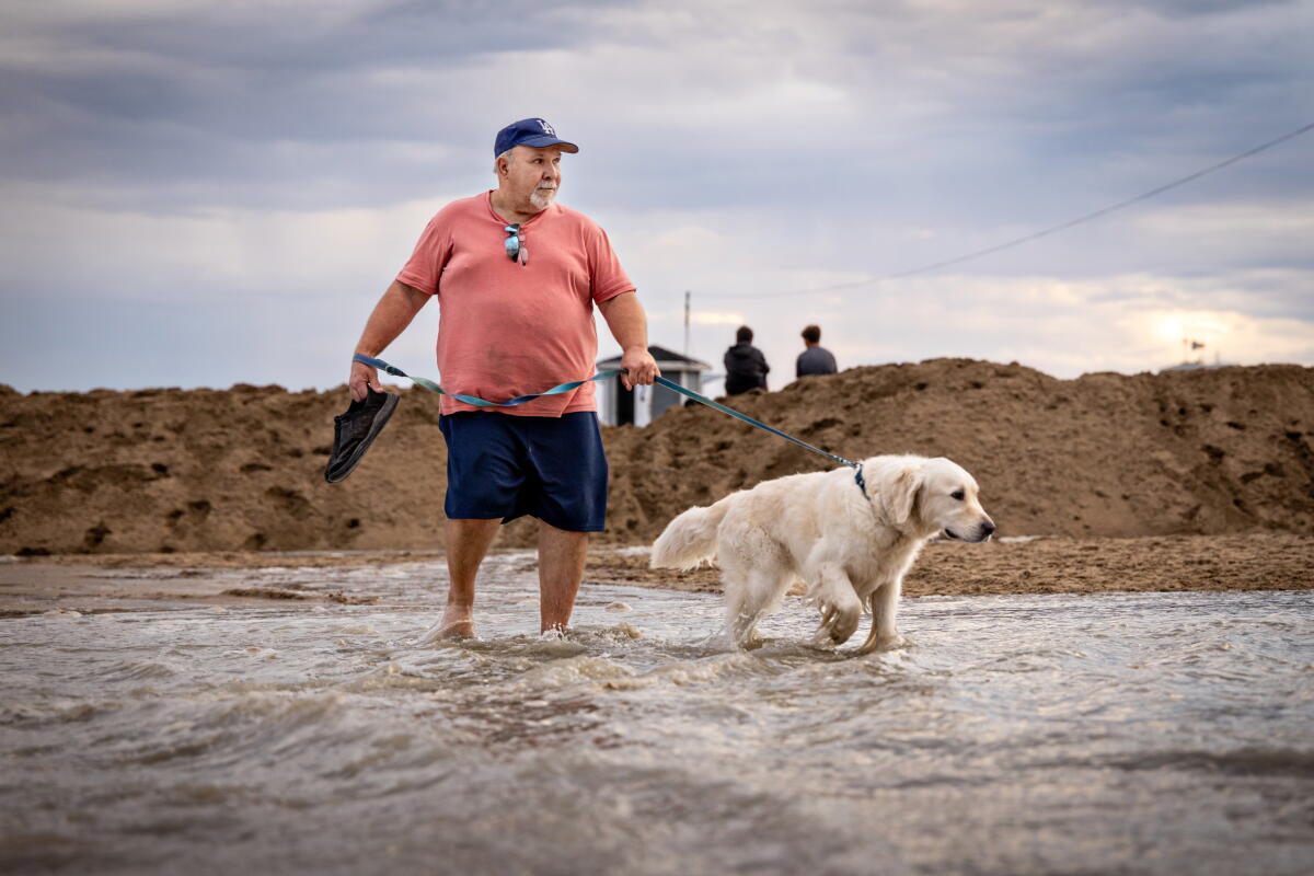 Mark Roslawski et son chien Benni traversent un parking inondé près de la jetée de Seal Beach.