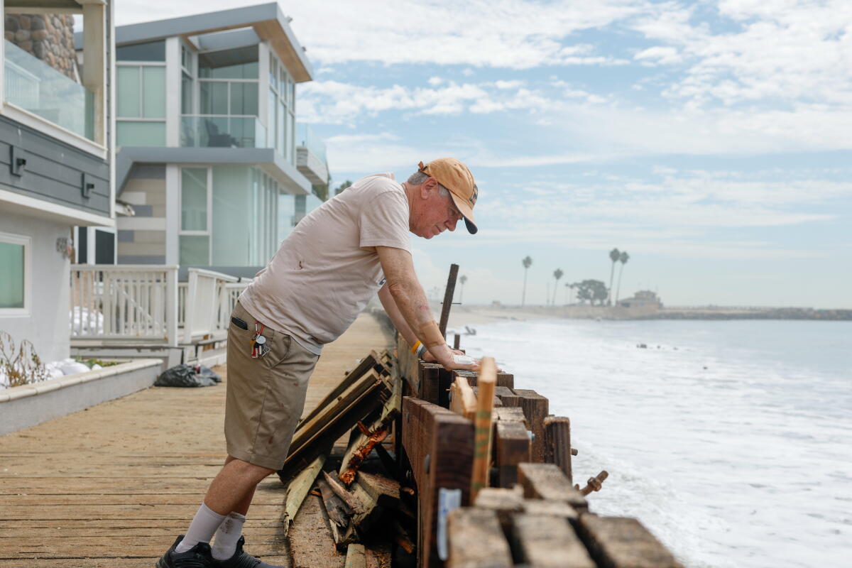 Ken Holt, un résident local, regarde la digue endommagée à l'extérieur de sa maison, sur la péninsule de Long Beach.