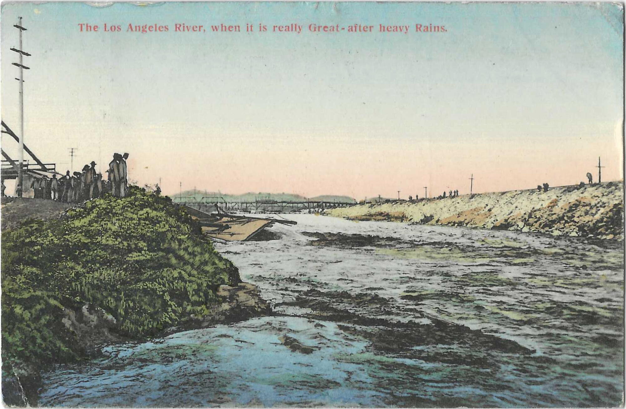 L'eau se précipite dans le bassin de la rivière LA, avec un pont en arrière-plan et des gens sur les deux rives