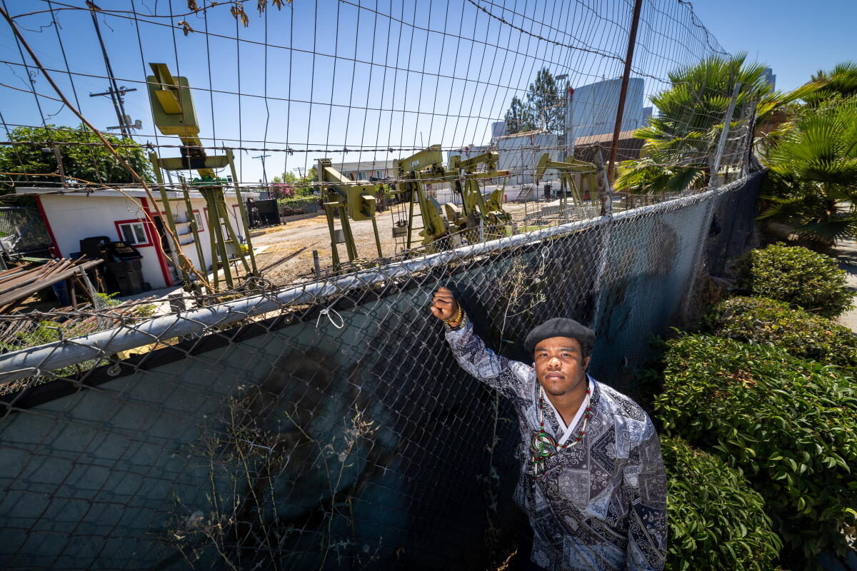 Le militant climatique Sim Bilal se tient à côté des pompes d’un champ pétrolier à Los Angeles en 2024.