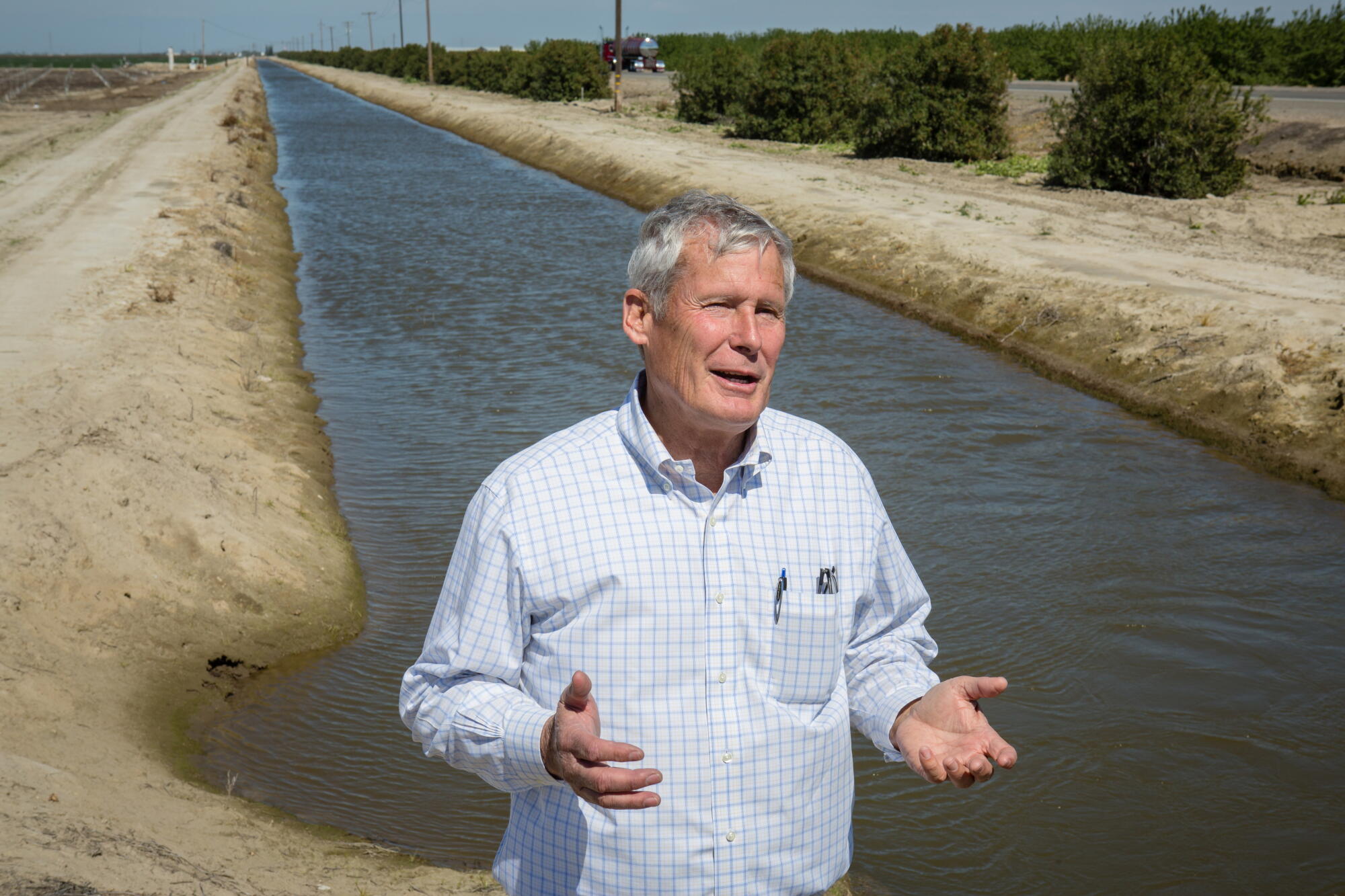 Don Cameron se tient à côté d'un canal d'irrigation où sa ferme puise l'eau de la rivière Kings.