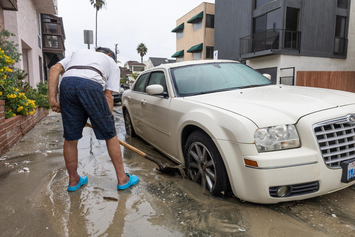 Robert Wells enlève le sable de ses pneus de voiture samedi à la 69e place de la péninsule de Long Beach.