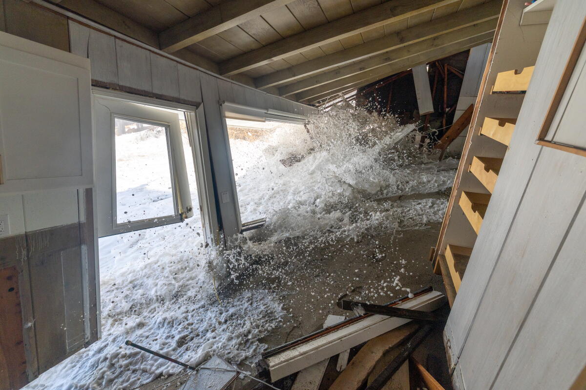 Une vague entraînée par la marée haute et les hautes vagues s'écrase sur une maison en bord de mer.