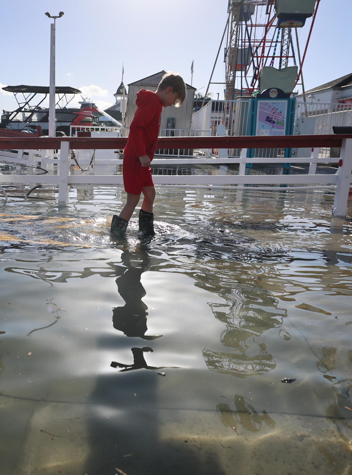 Un jeune garçon descendant du ferry de Balboa Island patauge dans les eaux de crue de la péninsule de Newport Beach.
